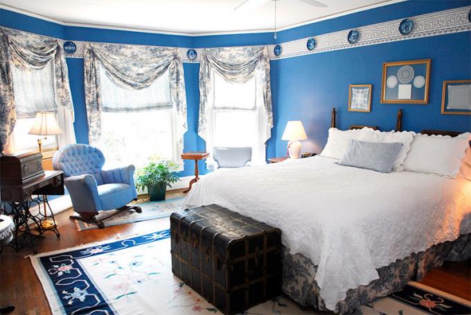 Foto van een slaapkamer met blauwe muren om ruimte te verminderen