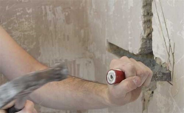 Shtroblenie muur met een hamer en beitel