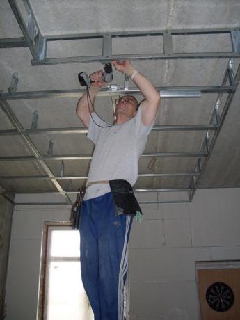 De foto toont de installatie van een verlaagd plafond.